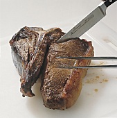 Beef. T-Bone-Steak tranchieren am Knochen einschneiden, Step