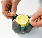 Close-up of hands binding lemon with artichoke, step 6