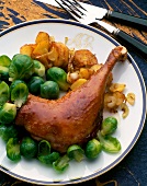 Goose leg in North German style with Brussels sprouts and roast potatoes on serving dish