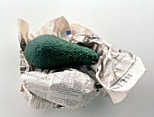Close-up of avocados in newspaper on white background