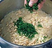 Close-up of parsley being added to pine kernels, rice and dill, step 3