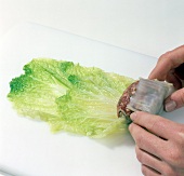 Chinese cabbage with meat filling being folded on cutting board, step 2