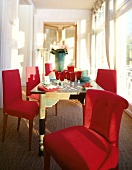 Holztisch und rote Stühle in hellem Zimmer, Gläser rot