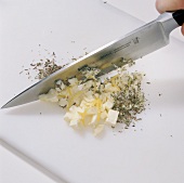 Garlic butter, dried marjoram and caraway seeds being chopped on cutting board, step 1