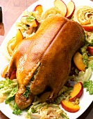 Golden brown glazed duck with filling of peach and vegetables on plate