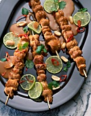 Turkey skewers with peanut sauce and lime slices on plate