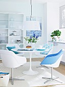 Esszimmer in Weiß mit rundem Tisch, Schalenstühlen & blauern Farbakzenten