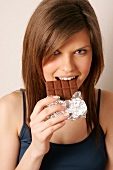 Portrait of woman with long hair eating chocolate, smiling
