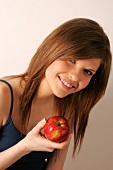 Portrait of woman with long hair biting into apple, smiling