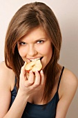 Portrait of woman with brown hair eating half red pear