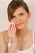 Portrait of pretty woman with brown hair cleaning her face with pad