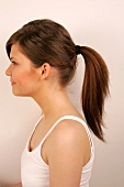 Side view of Magdalena woman with brown hair tied up in ponytail
