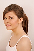 Portrait of gray eyed Magdalena woman with long brown hair tied up in ponytail, smiling