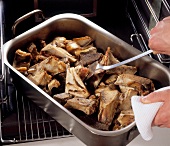 Beef in casserole being placed in oven for preparation of demi glace beef, step 1