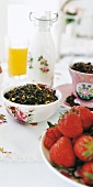 Tisch mit Rosentischdecke, Schale Teeblättern, Erdbeeren, Milchkanne