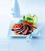 Asiatischer Rindfleischsalat mit Stäbchen auf einer weissen Platte