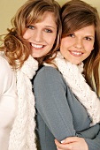 Portrait of two beautiful woman wearing sweater and scarf standing side by side, smiling