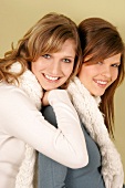 Portrait of two beautiful woman wearing sweater and scarf standing and smiling