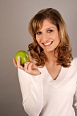 Portrait of young woman holding green apple and smiling