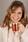 Portrait of beautiful woman in sweater holding cup of tea, smiling