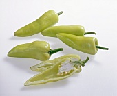 Halved and whole sweet green peppers on white background