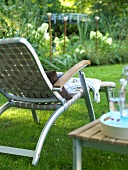 Deckchair aus Alu und Gurtgeflecht steht auf einer Wiese im Garten