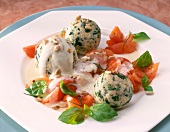 Spinach dumplings with cheese sauce and tomatoes on plate