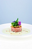 Tuna tartare with grilled artichokes and wild herb salad on plate