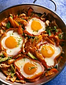Close-up of fried eggs with carrots, peppers, turkey cutlets and bacon in pan