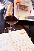 Notebook and glass of red wine on table, Havana Hills Winery, Philadelphia, South Africa