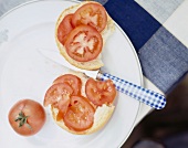 Bread with fresh tomato slices and spreading knife on plate