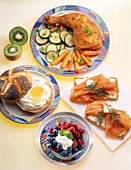 Chicken leg with vegetables, bread rolls salmon and berries with cottage cheese on plates