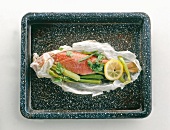 Fish garnished with vegetables in food paper on serving tray