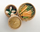 Sliced asparagus, carrots with chicken in basket against white background