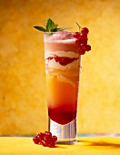 Refreshment drink made of ice cream, orange juice and red currant in glass