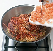 Tomatoes being added to lobster in pan, step 4