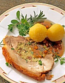 Fried pork meat with mushrooms, potato dumplings and herbs on plate