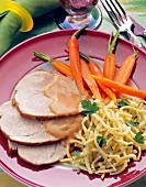 Roast boneless meat with carrots and noodles on plate