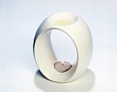 Close-up of white round candle holder with lit tea light candle