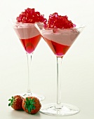 Two glasses of strawberry jelly with cream and jelly cubes in glass