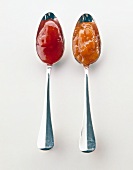 Jams from rose hips and sea buckthorn berries in spoon on white background