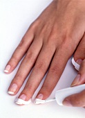 Close-up of woman applying white nail paint on one hand