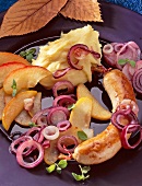 Putenbratwurst mit Zwiebelgemüse, Kartoffelpüree und Äpfeln auf Teller