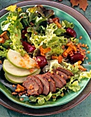 Close-up of green salad with turkey liver, apples and chanterelles on plate