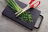 Chopped chives with scissors on chopping board