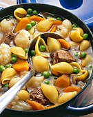 Close-up of noodle soup with beef shin, peas, carrots and Brussels sprouts in pot