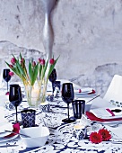 In schwarz-weiß gedeckter Tisch mit roten Servietten und Blüten