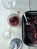 Plum jam being filled into glass from baking dish