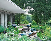 Terrasse am Teich im Wald, viel Grün, Blumen, Liege, Tisch + Stühle