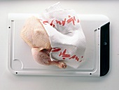 Raw chicken on cutting board with kitchen paper on white background